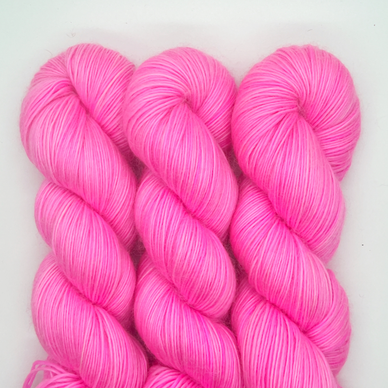 Three skeins of pink yarn on a white background