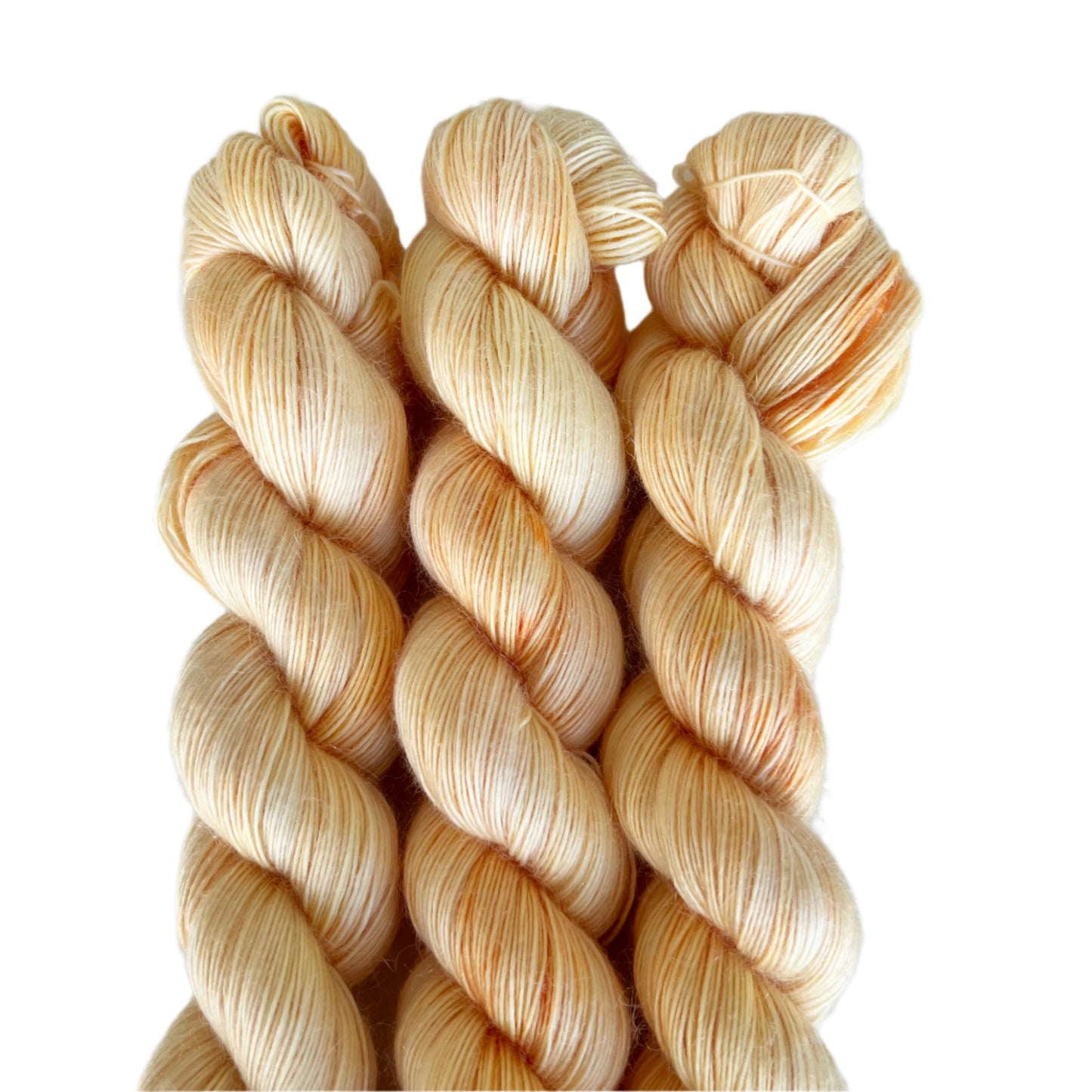 Three skeins of pale gold yarn on white background