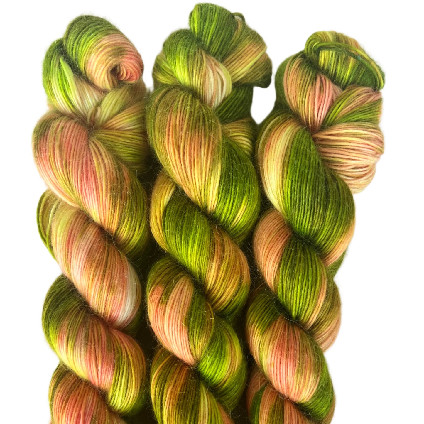 Three skeins of green and pink yarn on a white background