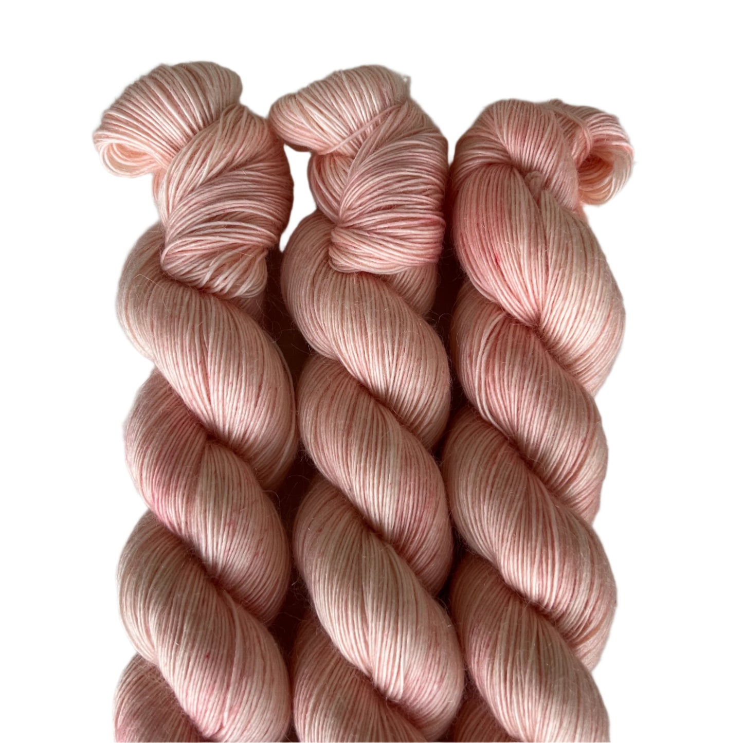 Three skeins pale pink yarn twisted together on white background