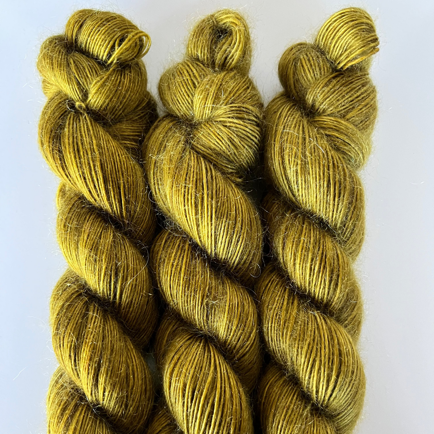 Three skeins of green yarn on a white background