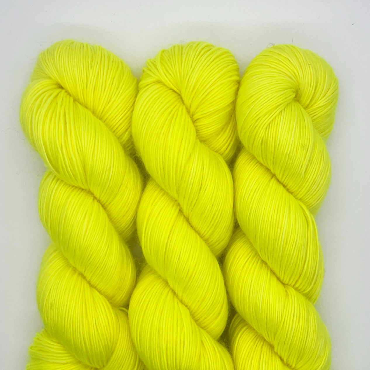 Three skeins bright yellow yarn on a white background