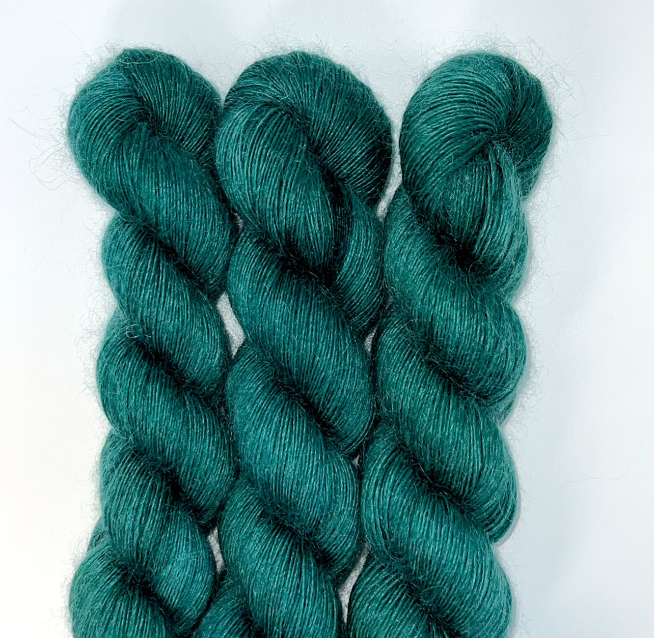 Three skeins of teal yarn on a white background